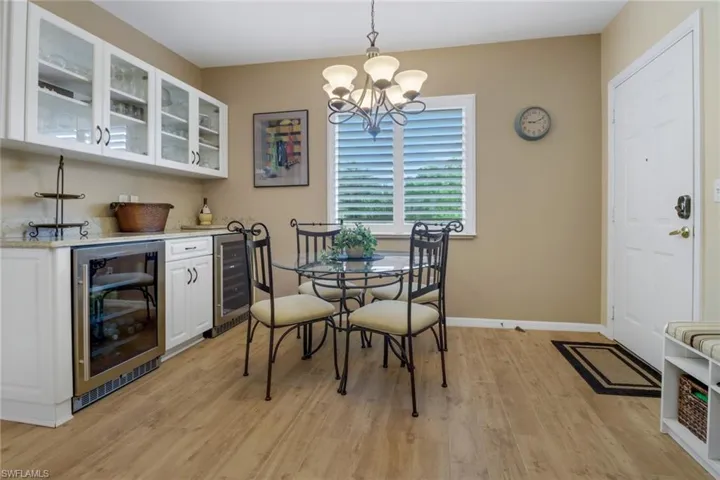 Dining area with beverage cooler, light wood-type flooring, and an inviting chandelier