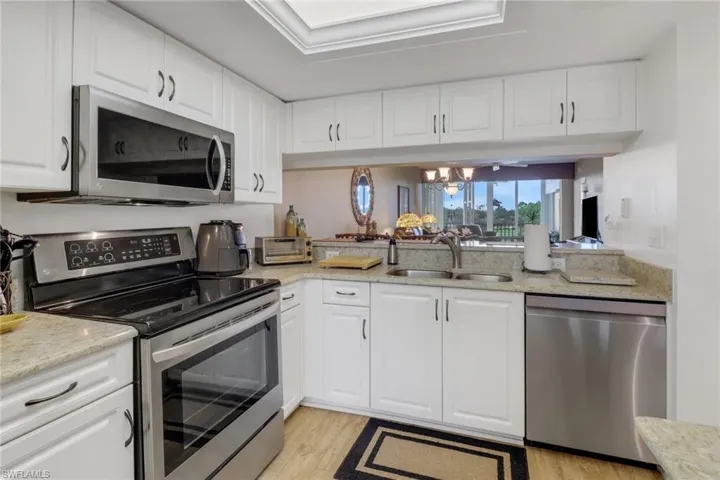 Kitchen with light hardwood / wood-style floors, sink, white cabinets, and stainless steel appliances