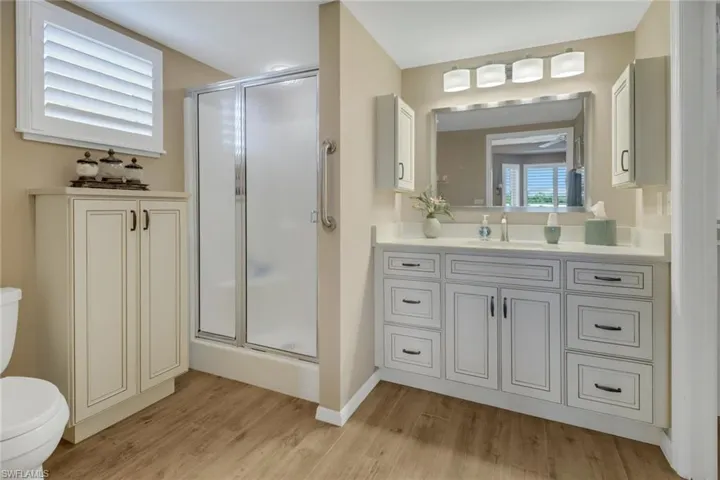 Bathroom featuring vanity, a shower with shower door, toilet, and hardwood / wood-style floors