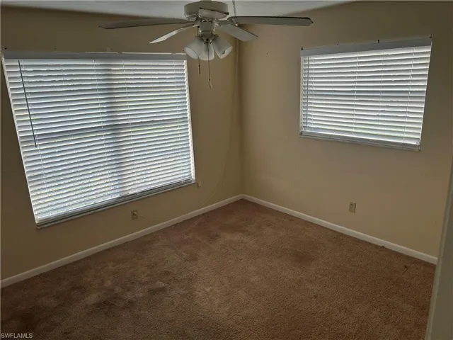 Unfurnished room with dark carpet and a ceiling fan