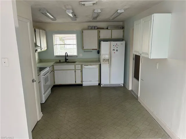 Kitchen with white appliances, light countertops, and dark flooring