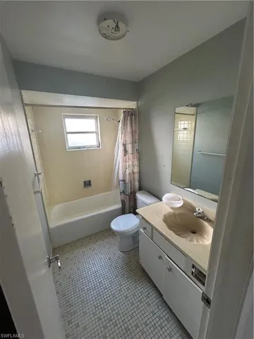 Full bath with vanity, shower / bathtub combination with curtain, and light tile patterned floors