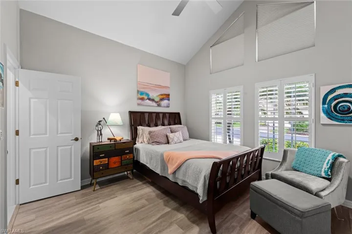Bedroom with ceiling fan, hardwood / wood-style floors, and high vaulted ceiling