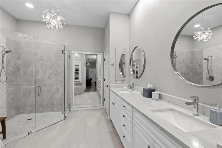 Bathroom featuring an inviting chandelier, an enclosed shower, and vanity