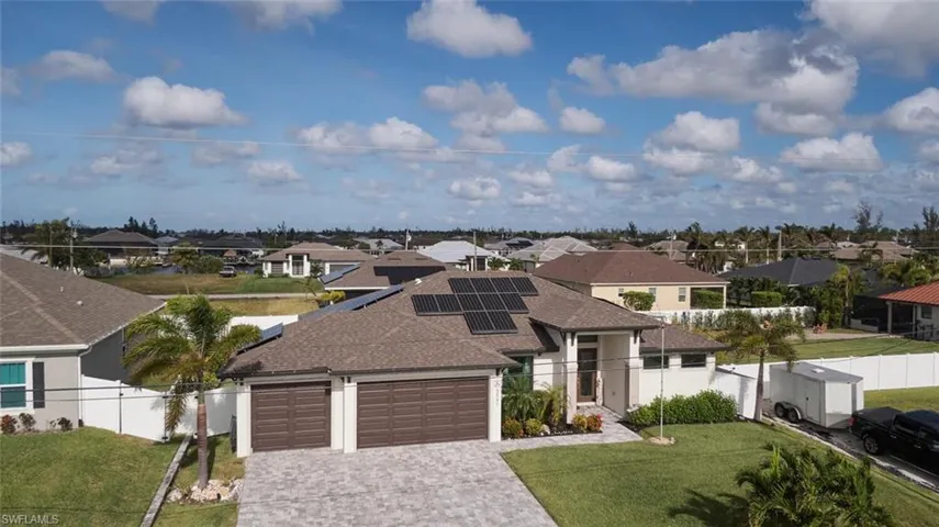 View of front of home featuring a front yard, solar panels, and a3 caar garage