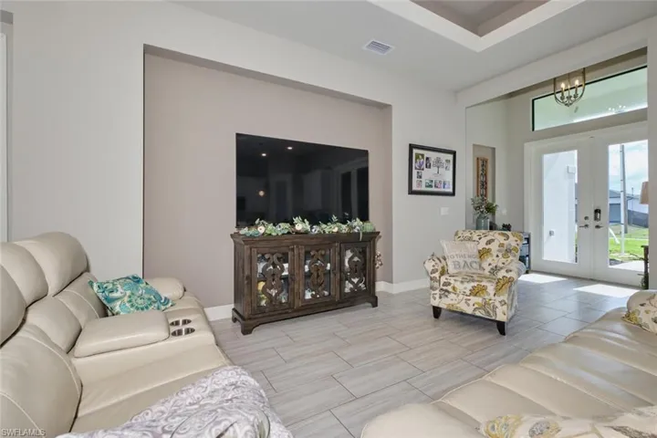 Living room with tray ceiling, french doors and ceiling fan