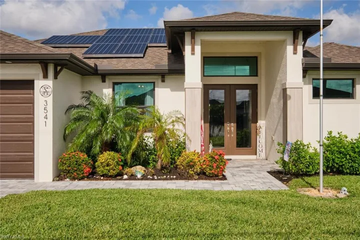 Property entrance with a lawn, solar panels, french doors, and a garage