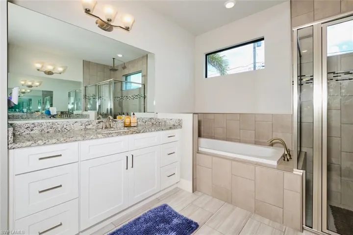 Bathroom featuring vanity, independent shower and bath, a wealth of natural light, and tile patterned floors
