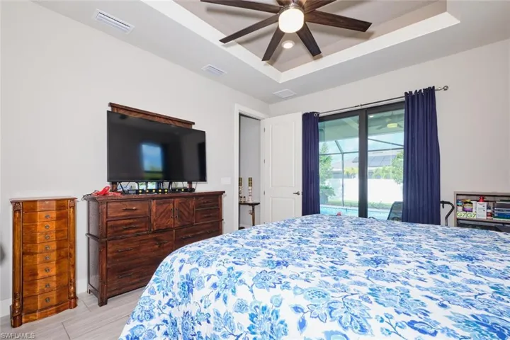 Bedroom featuring a tray ceiling, ceiling fan, and access to exterior