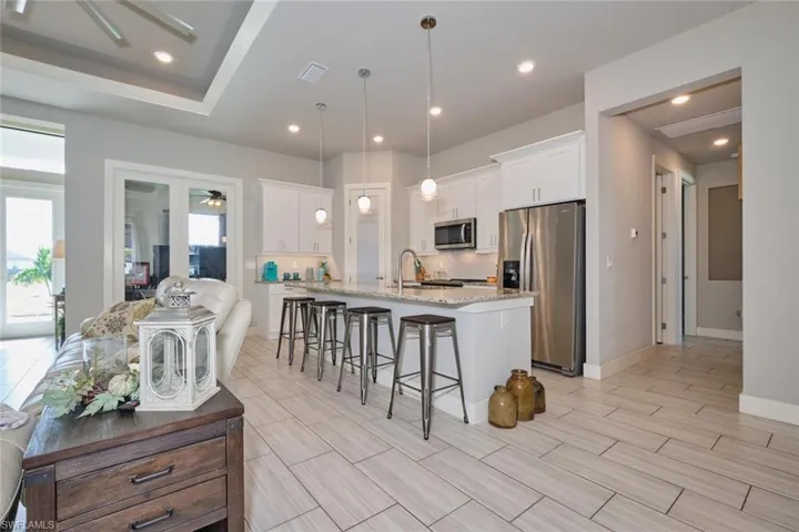 Kitchen with white cabinets, granite island and counters, stainless steel appliances, and decorative fixtures