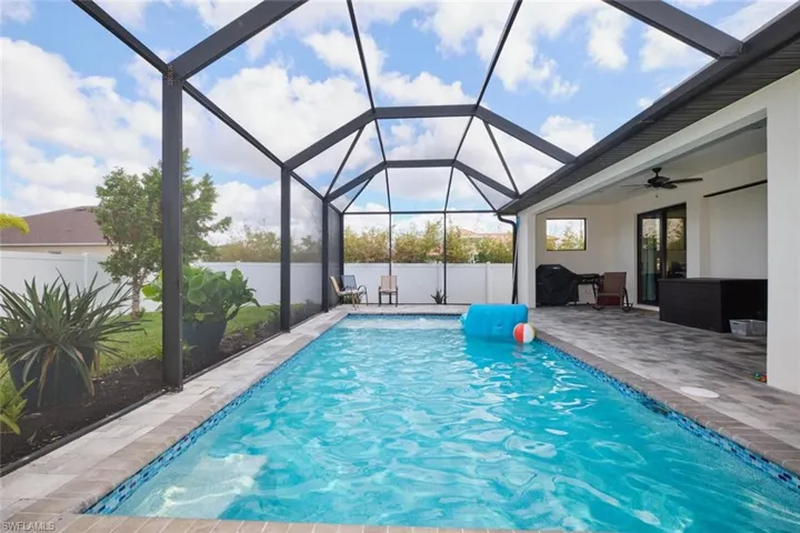 View of pool with a patio, screen enclosure, and ceiling fan