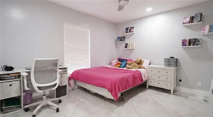 Bedroom featuring an office area, a ceiling fan, and light tile patterned floors