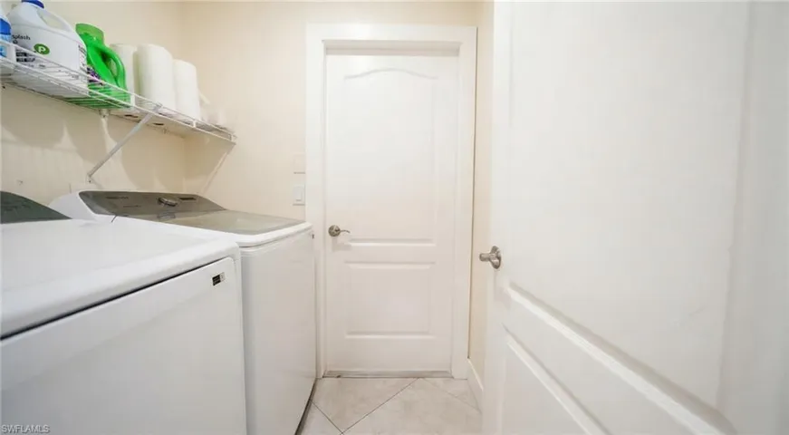Laundry room with washing machine and clothes dryer and light tile patterned floors
