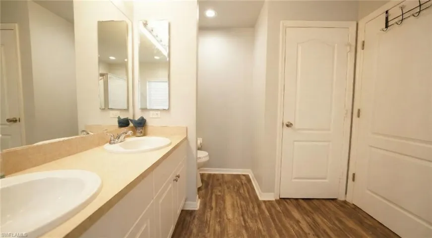 Bathroom with double vanity and dark wood-style floors