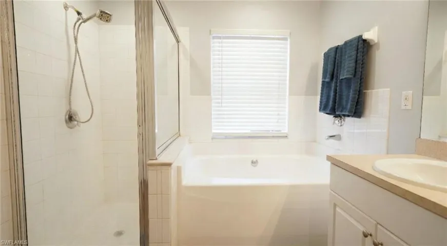 Bathroom with a garden tub, vanity, and a shower stall