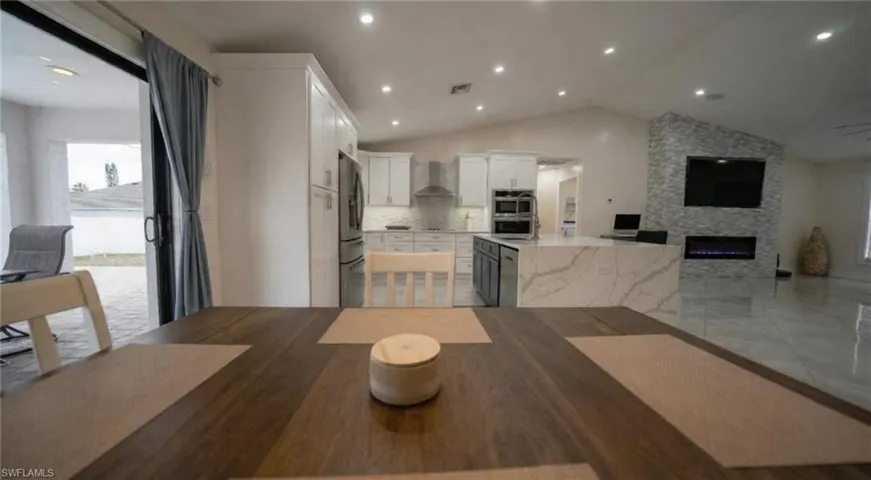 Dining area featuring lofted ceiling, a fireplace, and recessed lighting