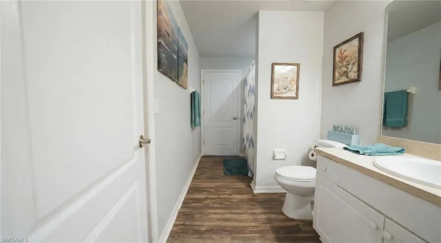 Full bath with vanity, a shower with curtain, and dark wood-type flooring