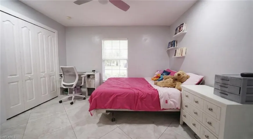 Bedroom with a closet, a desk, and a ceiling fan
