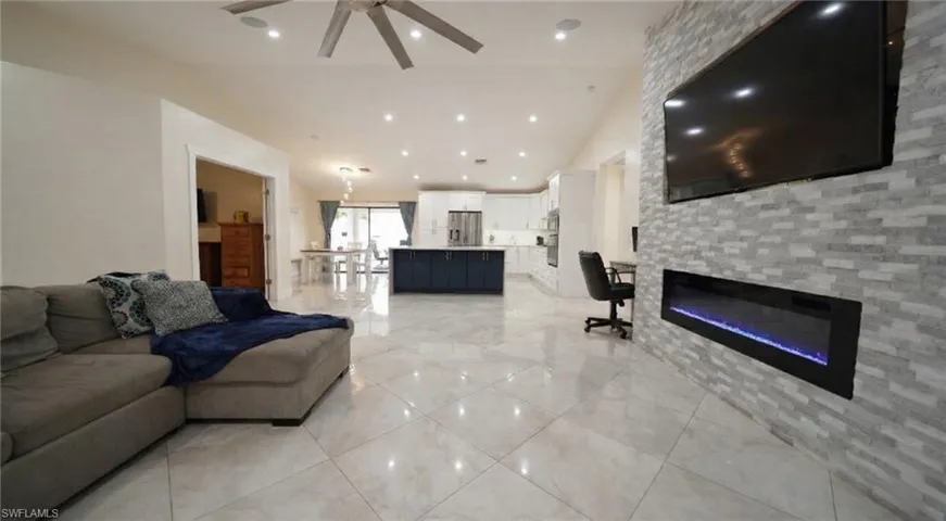 Living room featuring a fireplace, a ceiling fan, vaulted ceiling, and recessed lighting