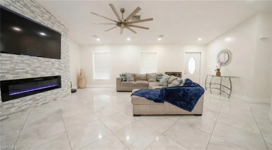 Living room featuring a large fireplace, ceiling fan, and recessed lighting