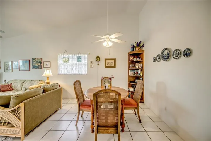 Casual dining with high vaulted ceiling, ceiling fan, and light tile floors