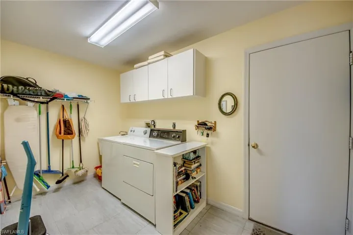 Laundry room with washer and dryer, cabinets, laundry tub, and light tile floor.