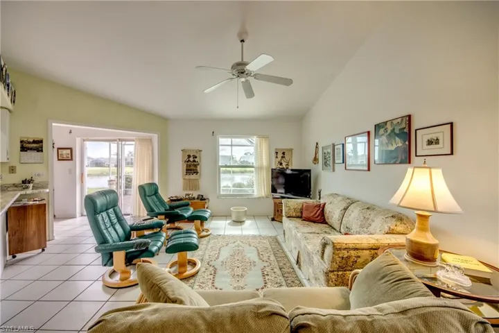 Family room with lofted ceiling, ceiling fan, and light tile floors