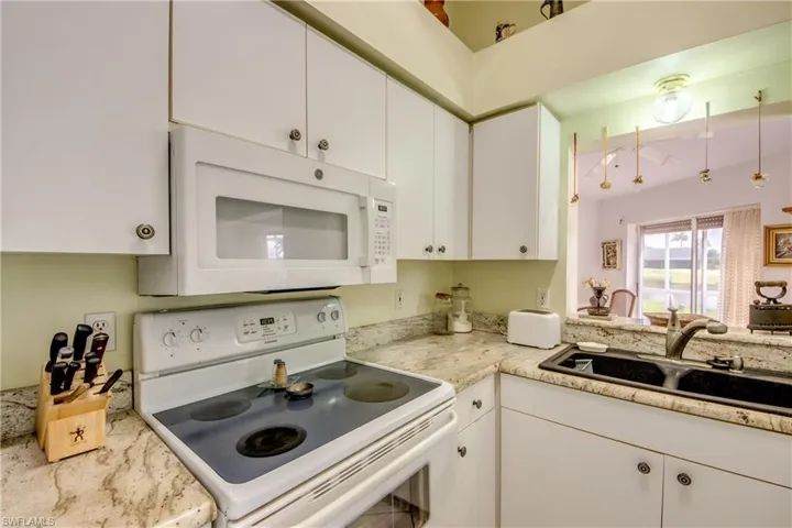 Kitchen featuring solid surface sink, white cabinetry, and white appliances