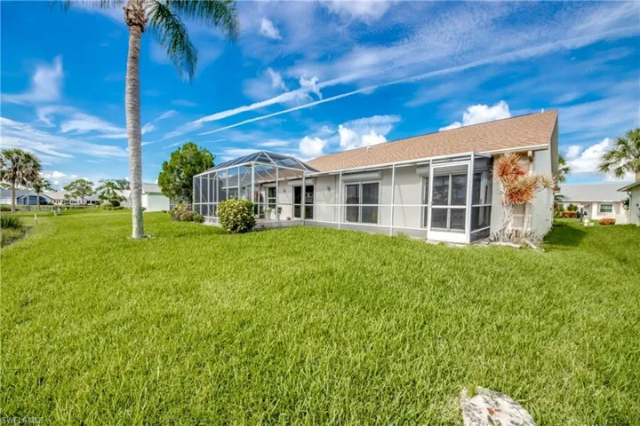 Back of property featuring large screen lanai and a yard