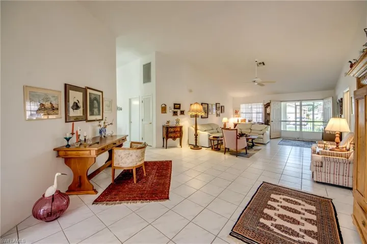 Living room featuring high vaulted ceiling, ceiling fan, and light tile floors