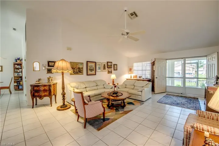 Living room with high vaulted ceiling, ceiling fan, and light tile flooring