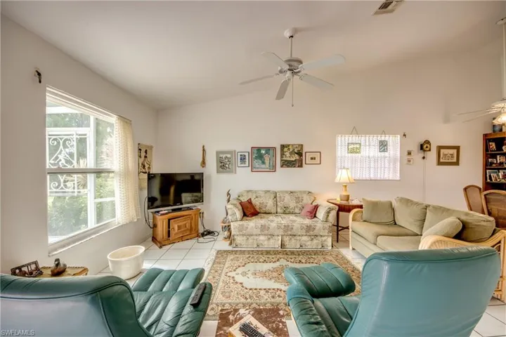 Family Room with a healthy amount of sunlight, vaulted ceiling, ceiling fan, and light tile floors