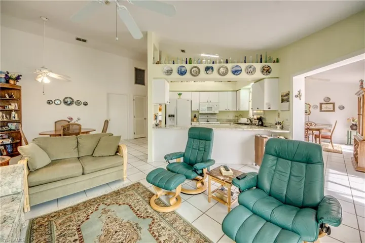 Family room with ceiling fan, a high ceiling, and light tile flooring