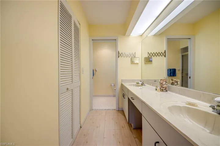 Bathroom featuring tile flooring, double sink, and vanity with extensive cabinet space.  Closet is massive!