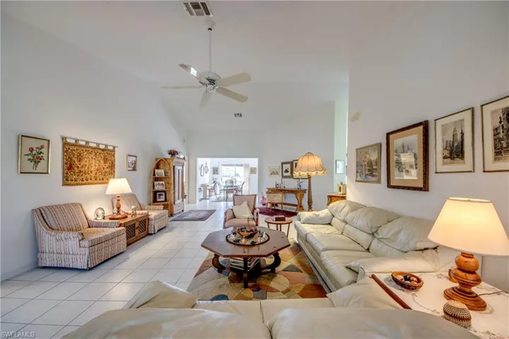 Living room featuring high vaulted ceiling, ceiling fan, and light tile floors