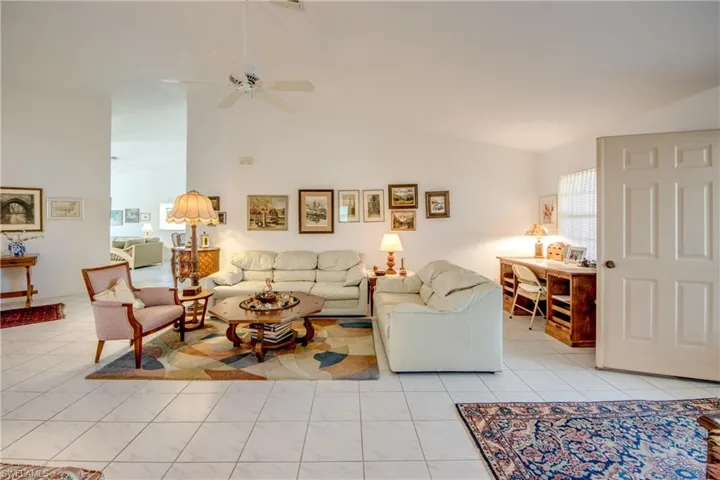 Living room with high vaulted ceiling, ceiling fan, and light tile flooring.  Looking to Family Room doorway