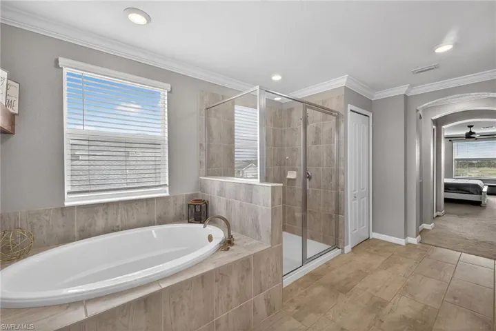 Ensuite bathroom featuring a bath, a shower stall, ornamental molding, ceiling fan, and recessed lighting