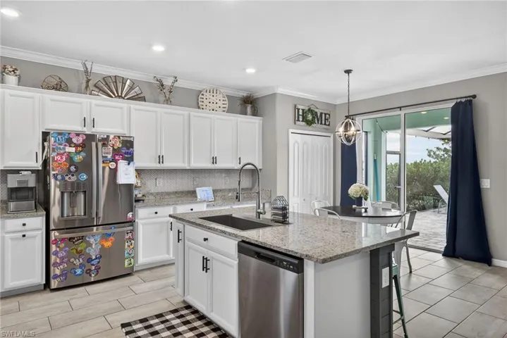 Kitchen featuring appliances with stainless steel finishes, white cabinets, crown molding, decorative backsplash, and light stone countertops