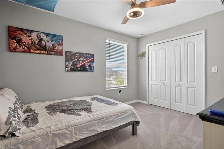 Carpeted bedroom featuring ceiling fan and a closet