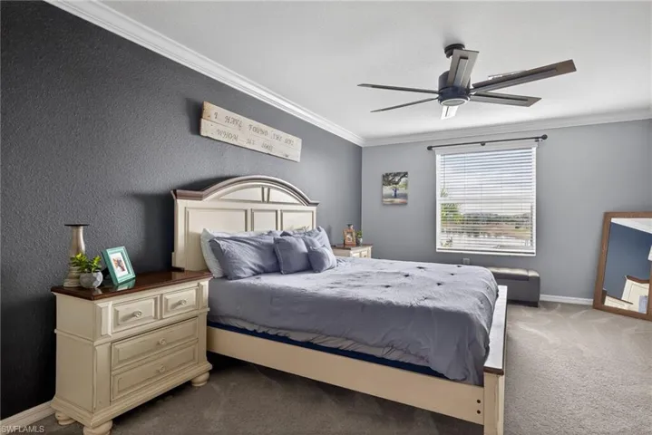 Bedroom with light colored carpet, crown molding, a textured wall, and a ceiling fan