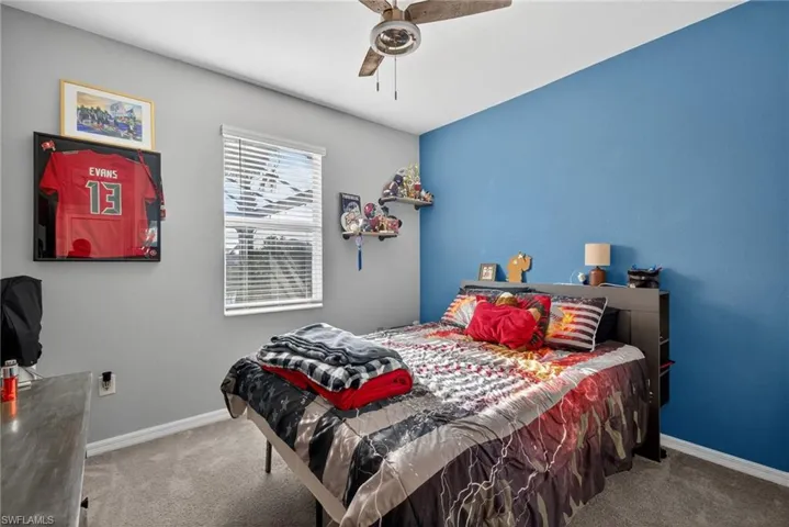 Carpeted bedroom featuring a ceiling fan and baseboards