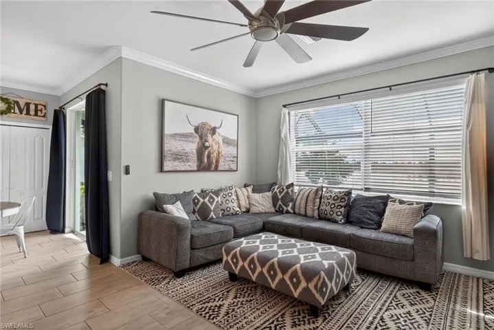 Living room featuring ornamental molding, wood tiled floors, and a ceiling fan
