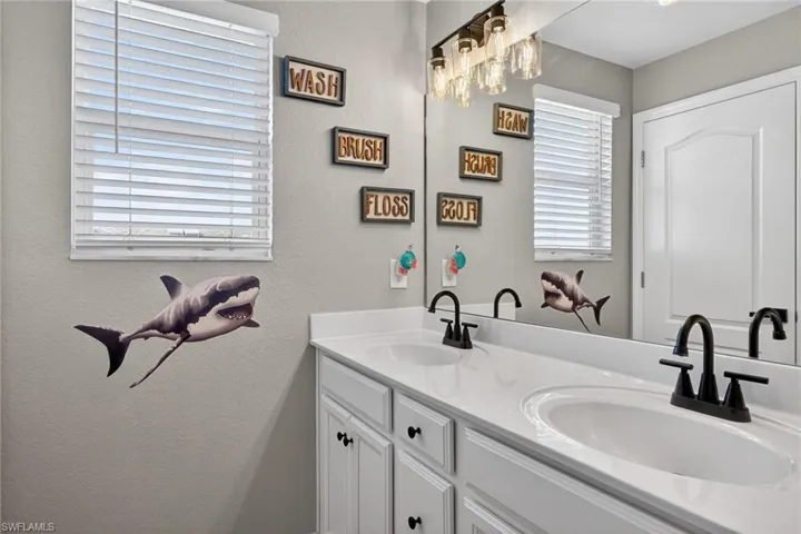 Full bath featuring double vanity and a textured wall