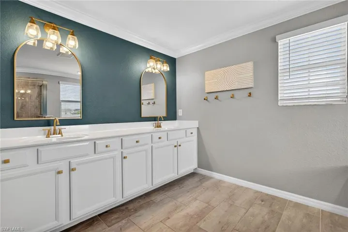 Bathroom featuring a textured wall, double vanity, ornamental molding, an enclosed shower, and wood tiled floors