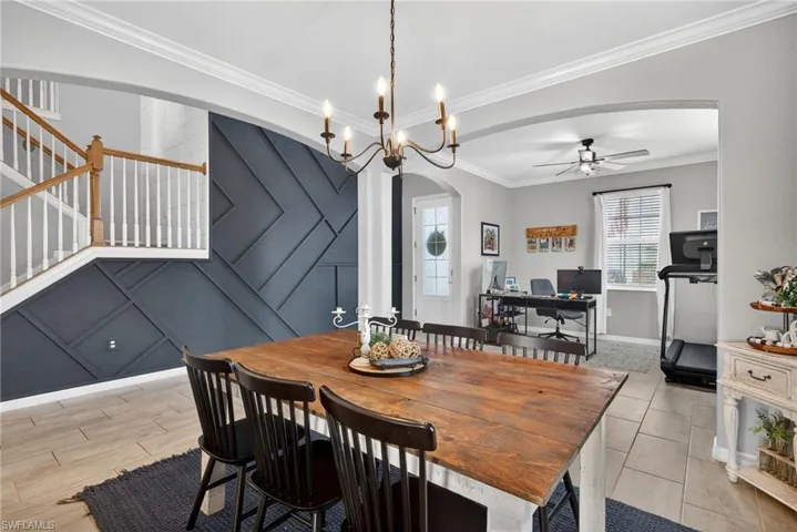 Dining room with arched walkways, crown molding, a desk, ceiling fan, and a decorative wall