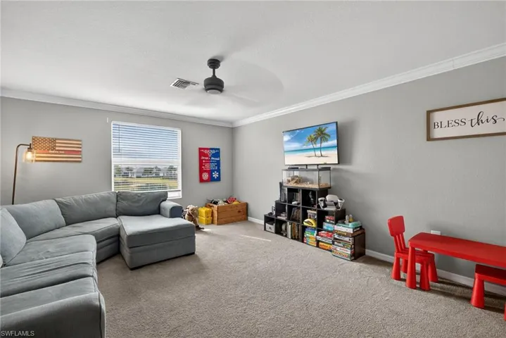 Carpeted living room featuring crown molding and ceiling fan