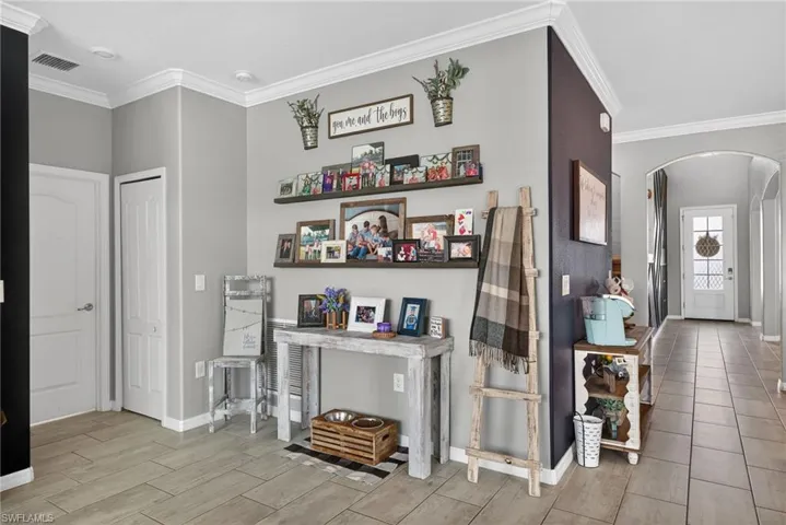 Entrance foyer with crown molding, arched walkways, and wood tiled floors