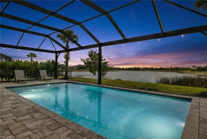 Swimming pool featuring glass enclosure, a patio, a water view, and a sunroom