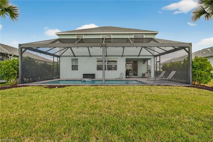 Rear view of property featuring glass enclosure, a sunroom, a yard, and an outdoor pool