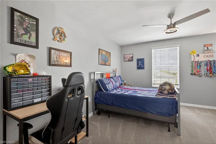 Carpeted bedroom with a textured ceiling, a ceiling fan, and a textured wall